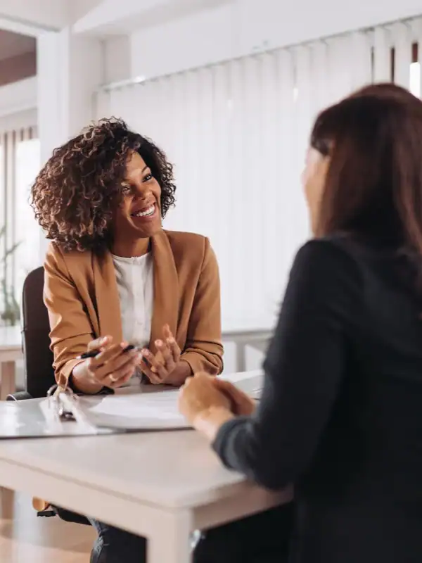 Two business women having a professional conversation in an office setting.